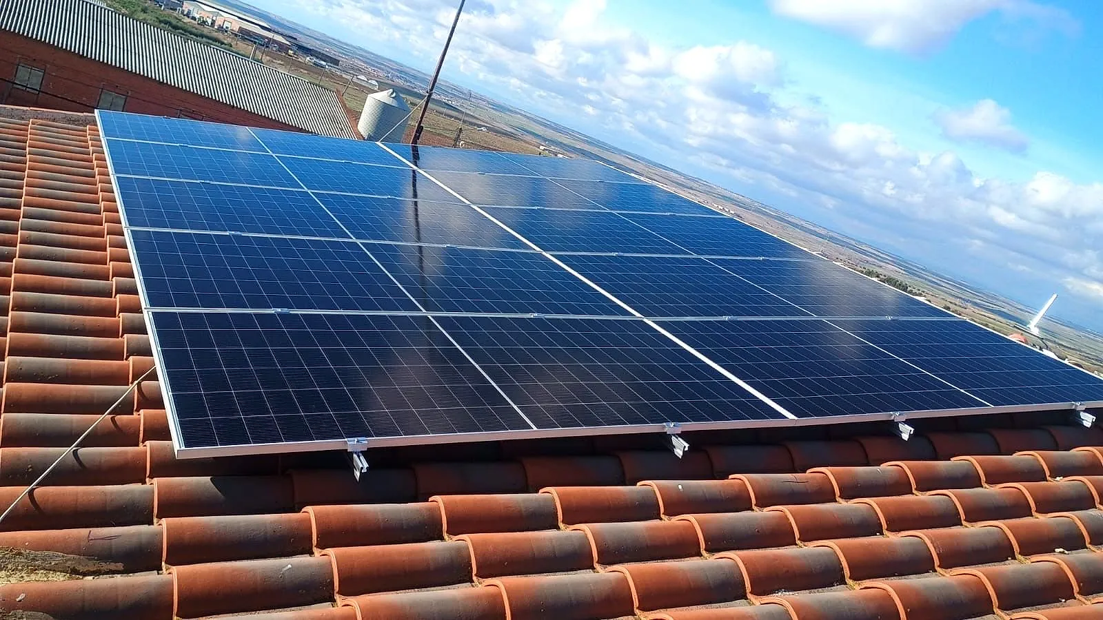 Detalle de paneles solares monocristalinos fijados con soportes sobre un tejado de teja