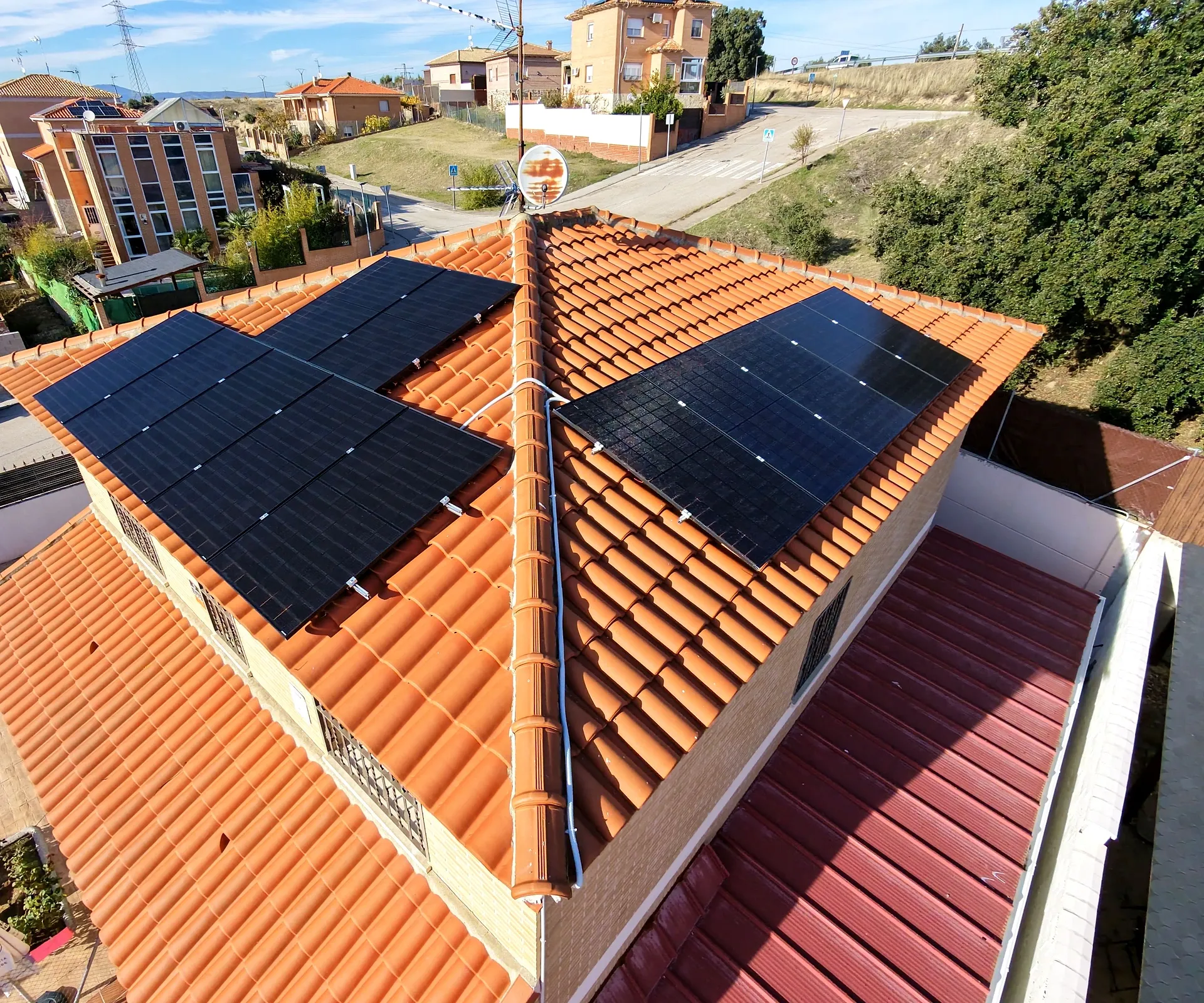 Vista aérea de una vivienda con paneles solares negros en las dos aguas de su tejado de teja cerámica